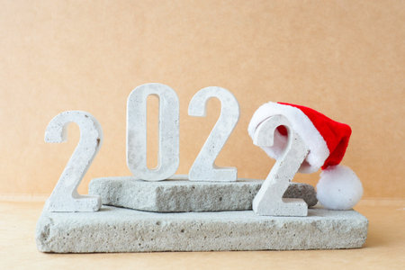 Celebrating the new year 2022. Number 2022 in concrete numbers with a New Year's hat on concrete...