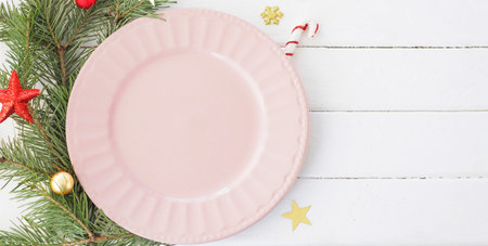 Christmas table setting. empty pink plate fir branches, snowflakes and stars. copy space.