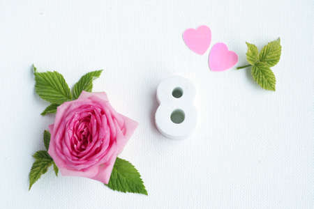 concrete number 8 and a beautiful rose with petals and hearts on a white background.の写真素材