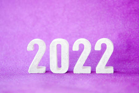 Concrete numbers 2022 on purple glittering background and falling snow. copy space.の写真素材