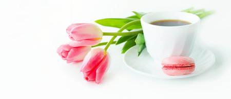 three pink tulips, macarons and a cup of coffee on a white table.の写真素材