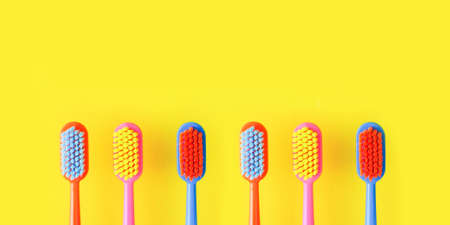 baner of multi-colored toothbrushes on a bright yellow background. copyspace.の写真素材