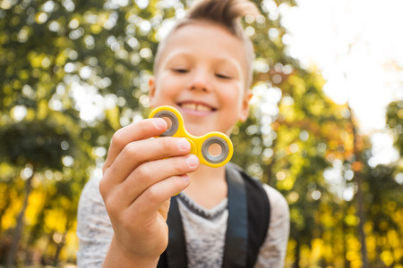 Close up portrait of beautiful boy with yellow spinner and smile. Happy and fun child playing with spinnerの写真素材