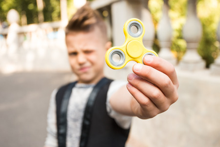 Close up portrait of beautiful boy with yellow spinner and smile. Happy and fun child playing with spinnerの写真素材