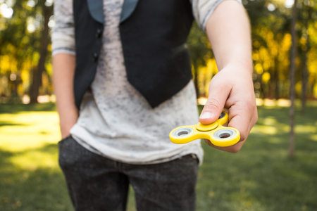 Boy's hands with spinner. Casual beautiful boy in style clothes with spinnerの写真素材