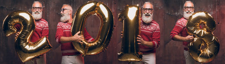 Senior bearded man holding numbers 2018 and smile. Santa Claus wishes Merry Christmas and a happy new year 2018!の写真素材