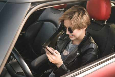 Business woman using internet on her mobile phone and s while sitting in the car. News in the...