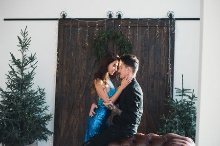 One moment to real passion kisses. Beautiful romantic couple in love kiss each other in elegant wear near Christmas Tree. Happy moments near my real biggest loveの写真素材