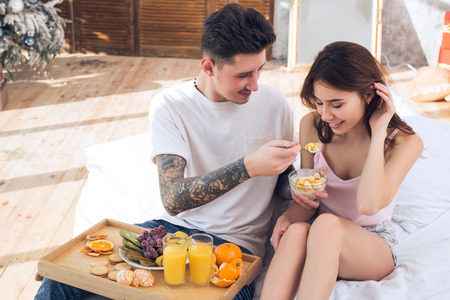 Beautiful couple in love feeds each other. Healthy Eating. Healthy breakfast in bed. Couple celebrating Christmas together.の写真素材