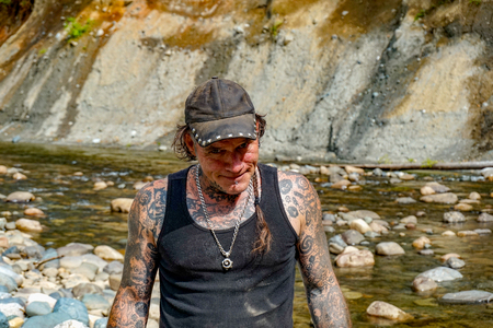 Tattooed Man With Smug Look On His Face, Standing Down At The Riverの写真素材