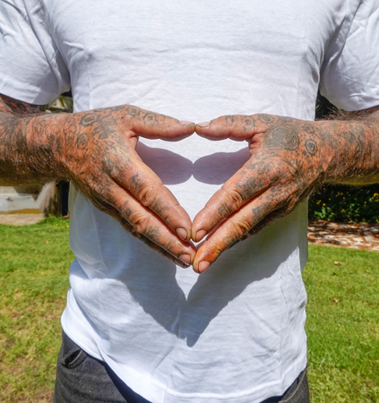 Adult Male with Dirty Tattooed Hands Making A Heart Signの写真素材