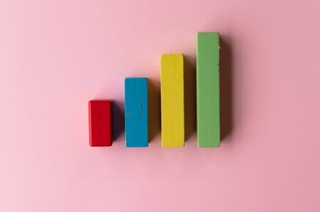 Colourful wooden toy block financial bar chart graph on pink color background - childrens nursery or retail business conceptの写真素材