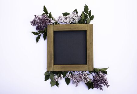 A blank wooden blackboard frame mock-up on a white background with lilac flowers and leaves - creative digital flat lay layoutの写真素材
