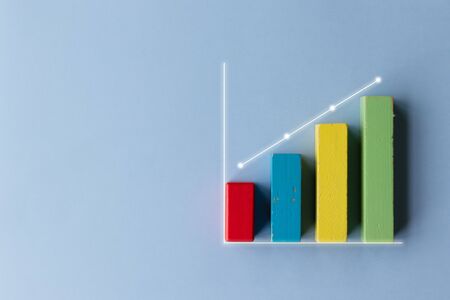 Colorful wooden toy block financial bar chart graph with upward trend line on blue color background - children's nursery or retail business conceptの写真素材