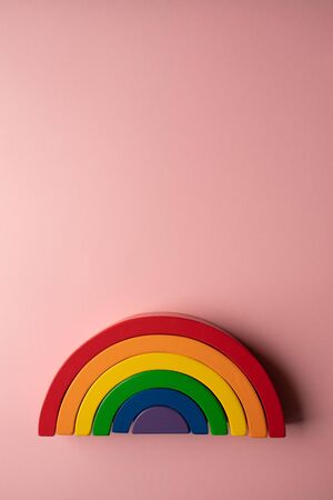 Bright wooden rainbow toy on a pink background with copy space - creative toy concept flat lay portraitの写真素材