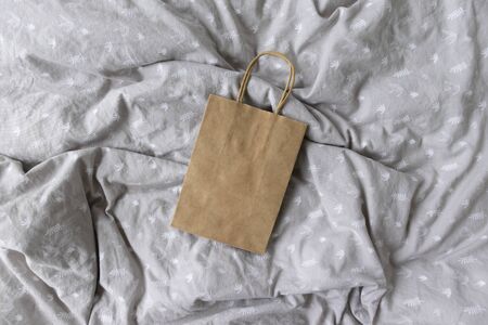 Blank Brown Paper Bag Mockup On a Grey Patterned Duvet Background - Paper Bag Mockup - Add Your Own Design - Styled Stock Photographyの写真素材