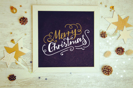 Christmas decorations and objects flat lay photo with black chalkboard frame and hand drawn inscription. Merry Christmas gift lettering on black board.の写真素材