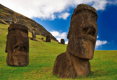 Moai statues against a clear blue sky and green grass field in the Rano Raraku Volcano in Easter Island, Rapa Nui National Park, Chile.の写真素材