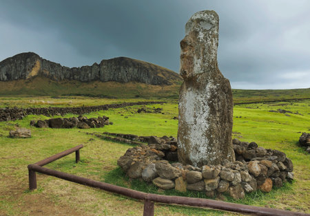One Moai statue surrounded by stones against a cloudy sky, green grass and plateau, Easter Island (Rapa Nui), Chileの写真素材