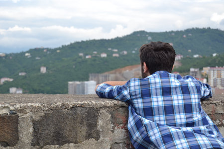 The man in the blue shirt put his hands on the wall. watching the view.の写真素材
