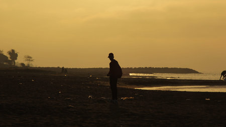 silhouette of the man by the sea in the sunset. (yellow sky)の写真素材