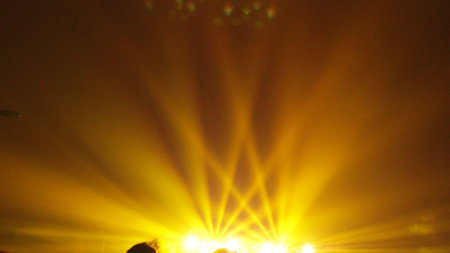 yellow concert spotlights. spotlights illuminating the sky. crowded concert