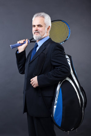 Studio shot of a smiling handsome business man who is going to play tennisの写真素材