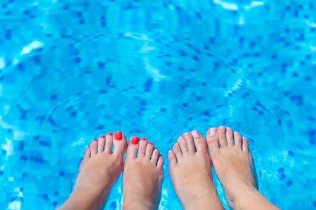 women feets on a background of water in swimming poolの写真素材