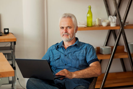 senior man with notebook sitting at the kitchen 