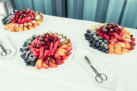 catering with Assortment of juicy fruits on plates on white  tableの写真素材