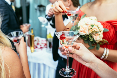 girls Drinking martini cocktails with red cherry on the weddingの写真素材