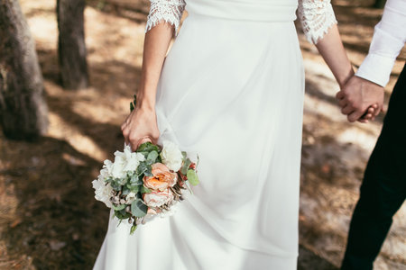 groom holding a bride hand with weding bouquet on wedding ceremonyの写真素材