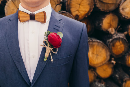 grooms with wooden bow-tie and red rose boutonniere on wooden background