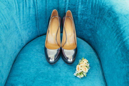 silvering bride shoes with wedding boutonniere on turquoise couchの写真素材