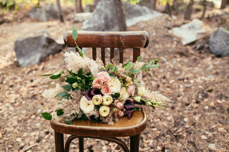 Bridal bouquet. The bride's bouquet. Beautiful bouquet of white, purple, pink flowers and greenery, lies on vintage wooden chairの写真素材