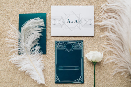 Blank stylized with dark turquoise card romantic invitation on peach carpet background. Top view