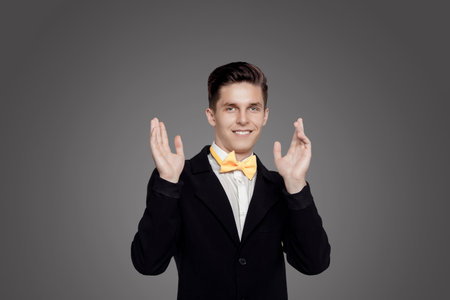 Young trendy man. Black suite, yellow bowtie, gray background. Portraitの写真素材