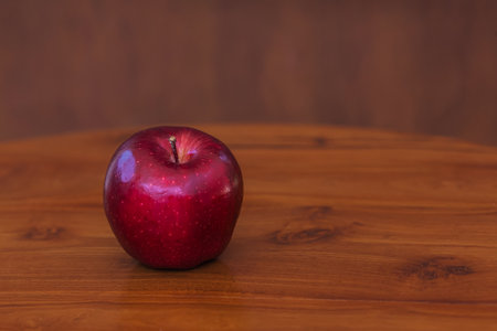 Red juisy apple on a brown wooden table and brown background. Close-upの写真素材
