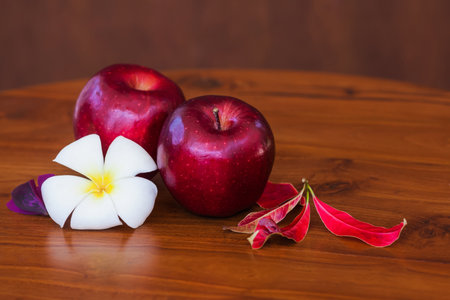 Red juicy apples with flower and leaves on wooden brown table and wooden background. Close-upの写真素材