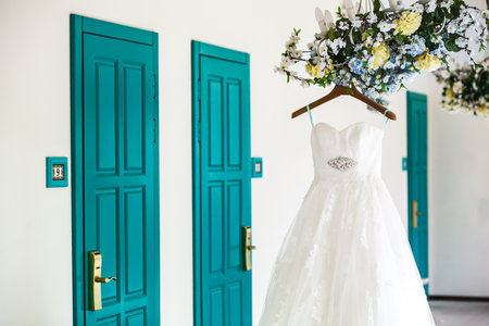 Beige wedding dress hangs on peg on chandelierの写真素材