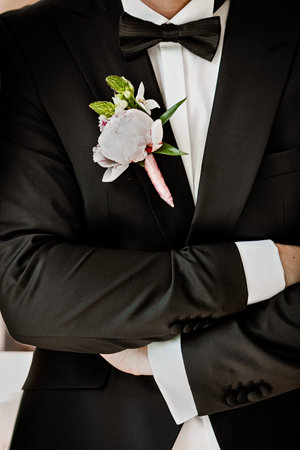 Pink peon boutonniere pinned to a grooms jacket