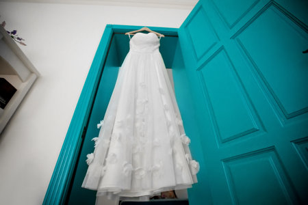 Beige wedding dress hangs on peg on doorの写真素材