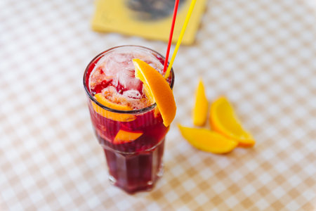 Red cocktail with straws and orange wedge in high glassの写真素材