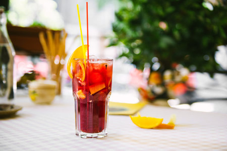 Red cocktail with straws and orange wedge in high glassの写真素材