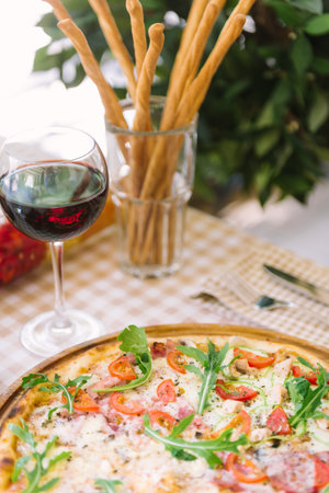 Pizza with glass of wine, on served tableの写真素材