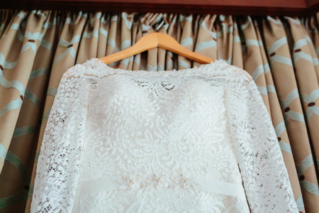 Bodice of a wedding dress hanging from a curtain poleの写真素材