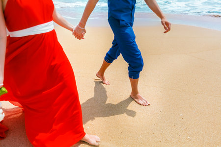 A couple walking together on the beach and holding hands. Close-upの写真素材