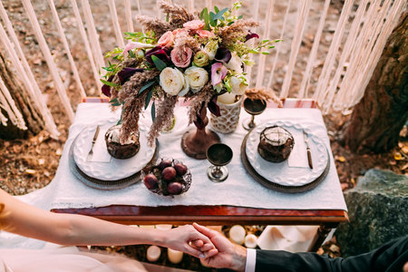 Wedding in the vintage style on outdoor. Couple holding hands. Flower compositionの写真素材