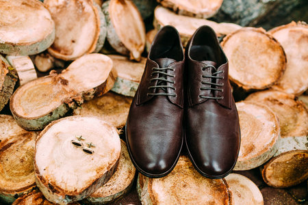 Groom's shoes and cufflinks on a wooden background. Men's accessories. Close-upの写真素材
