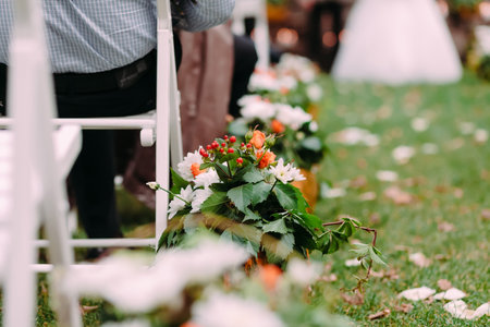 Decorations of white and orange flowers with green leaves decorations during outdoor wedding ceremonyの写真素材